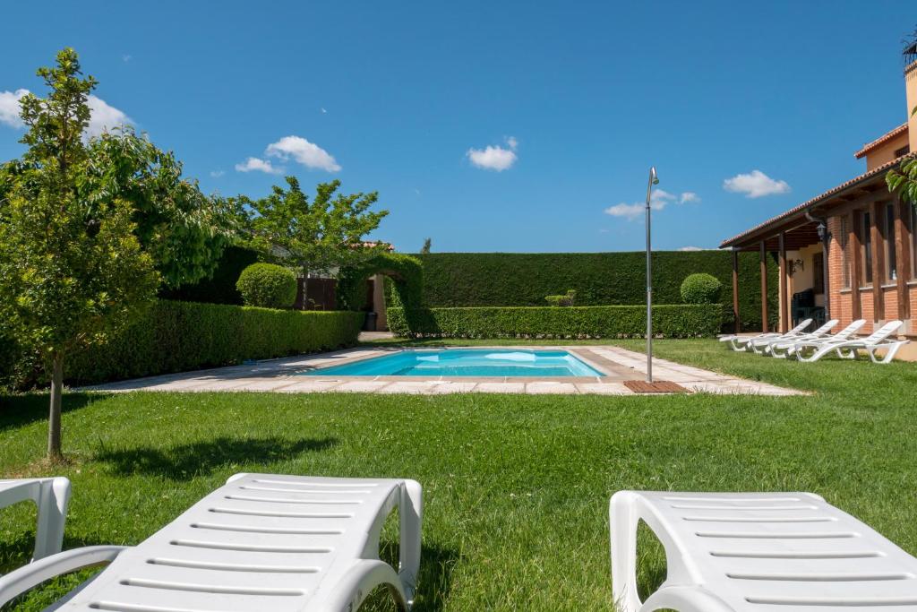 a yard with a swimming pool with lounge chairs at Casa Rural El Cuco in Robledillo