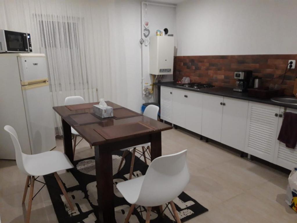 uma cozinha com uma mesa de madeira e cadeiras brancas em Sweet Home em Buzau