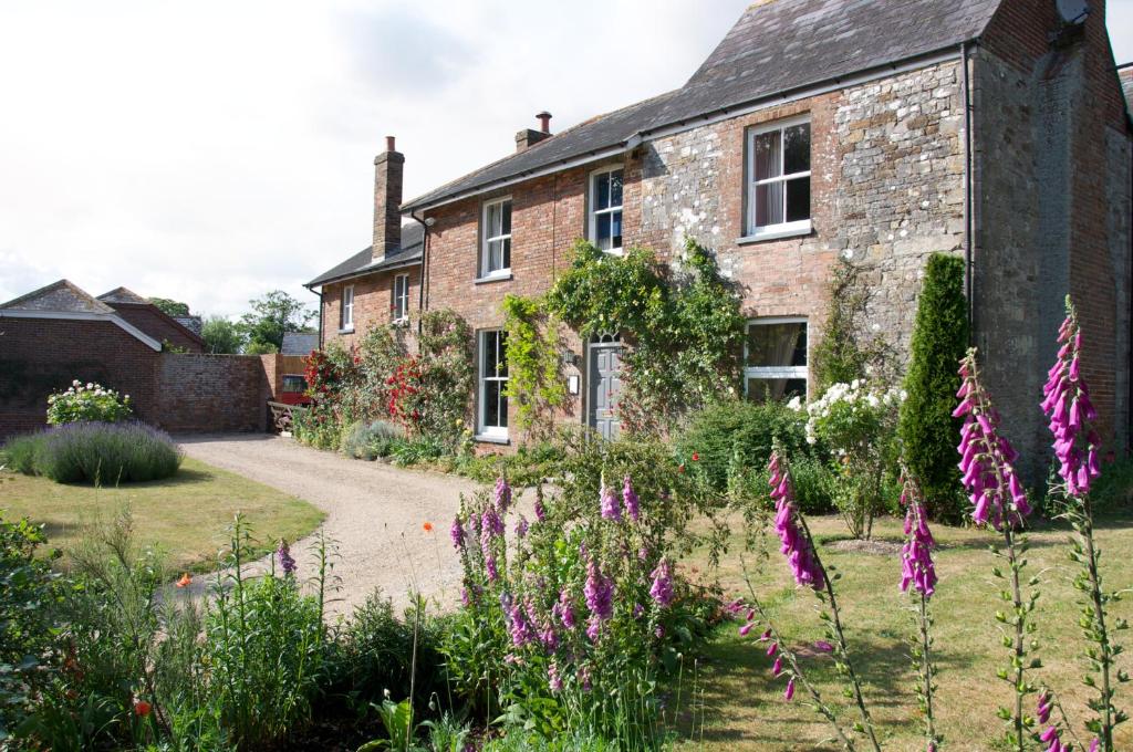 um jardim em frente a uma casa de tijolos com flores roxas em Heronshaw House em Hurn