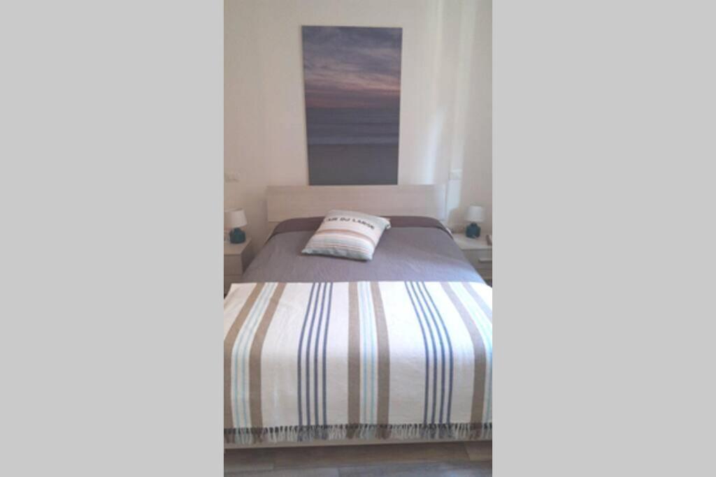 een slaapkamer met een bed met een gestreepte sprei bij Sea Lovers Italy Apartment in Porto Recanati
