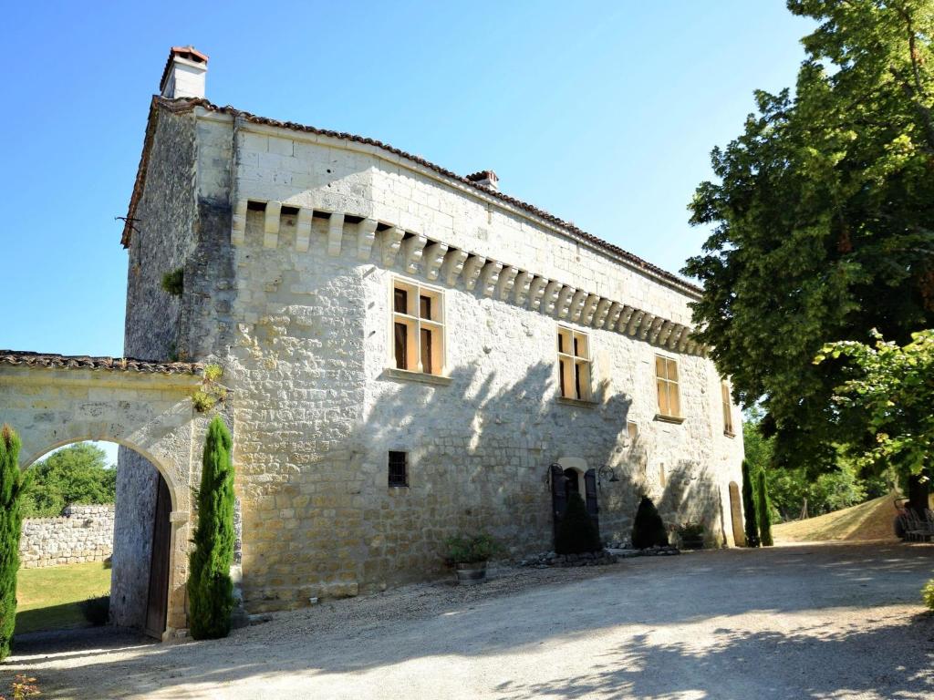 un antiguo edificio de piedra con un arco en un patio en Castle Retreat near Villages, en Saint-Caprais-de-Lerm