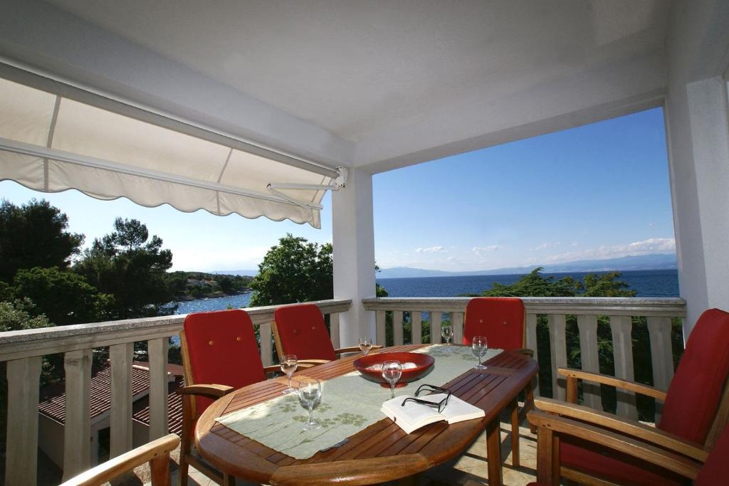 een tafel en stoelen op een balkon met uitzicht op de oceaan bij Apartment Andrina in Vantačići