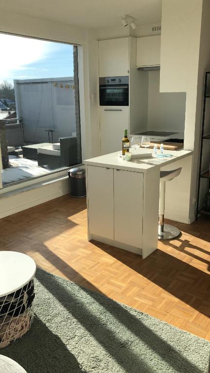 een keuken met witte kasten en een groot raam bij Gezellig 1 slaapkamer appartement nabij het stadscentrum in Hasselt