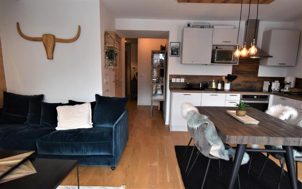 ein Wohnzimmer mit einem blauen Sofa und einem Holztisch in der Unterkunft VAUJANYLOCATIONS - Saphir 04 in Vaujany