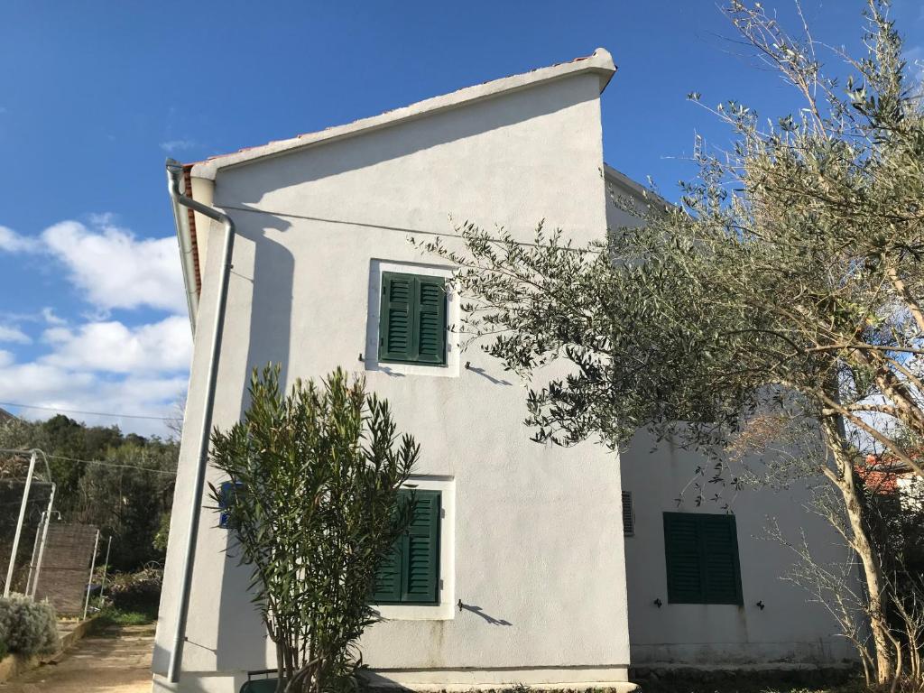 a white house with green shutters on it at Rustic House Miketa - Family Summertime in Lukoran