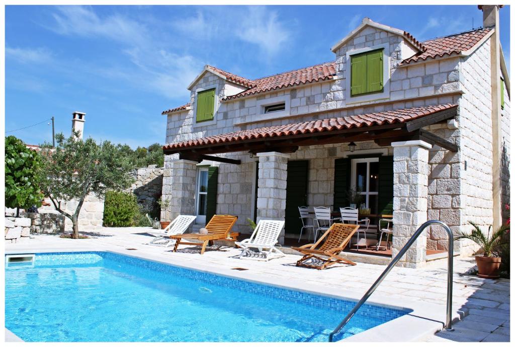 a villa with a swimming pool in front of a house at Villa Kate in Vrsine