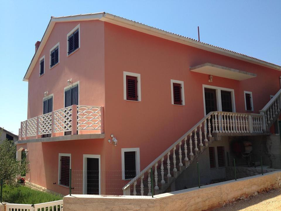 ein großes orangefarbenes Haus mit einem Balkon und einer Treppe in der Unterkunft Apartments Mira 1434 in Lun