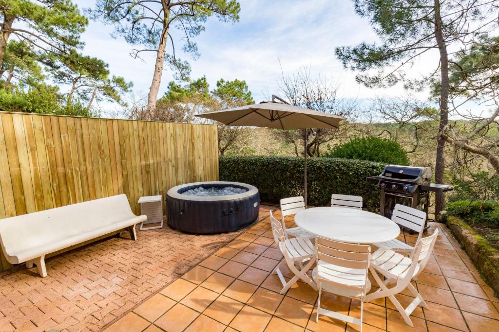 un patio con tavolo, sedie e griglia di Forest flat / Terrasse-spa-bbq-10min à pieds de la plage a La Teste-de-Buch