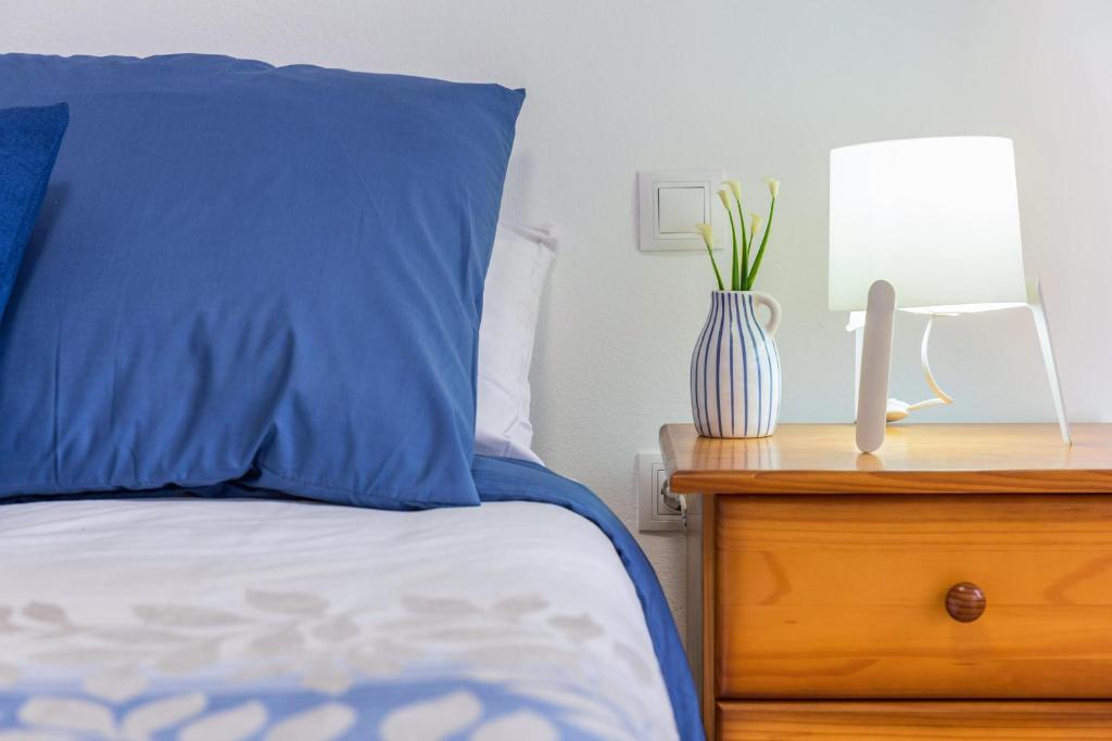 Cama con almohada azul y mesa con lámpara en Apartamento Las Playitas, en Tuineje