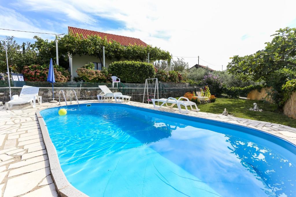 a swimming pool with chairs and a house at Villa Desin in Molunat