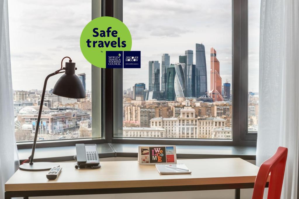 a desk with a lamp and a view of a city at AZIMUT Hotel Smolenskaya Moscow in Moscow