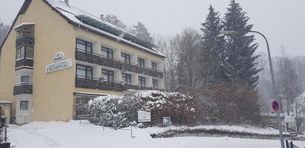 a building with snow on the ground in front of it at Panorama Hotel Pension Frohnau in Bad Sachsa