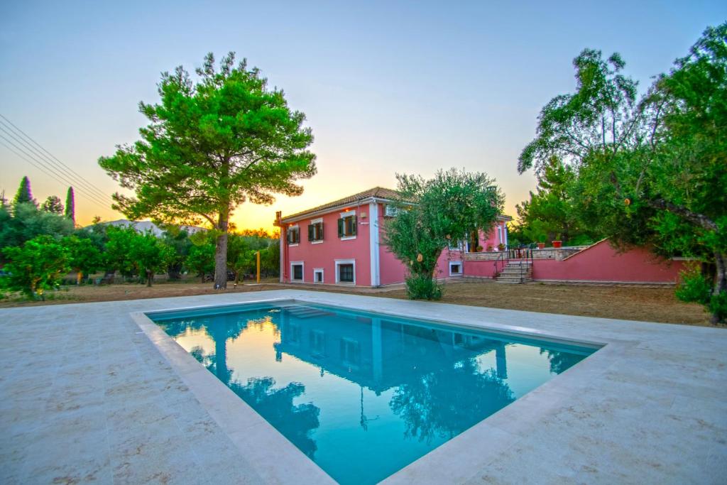 a swimming pool in front of a pink house at Doliva Estate in Laganas