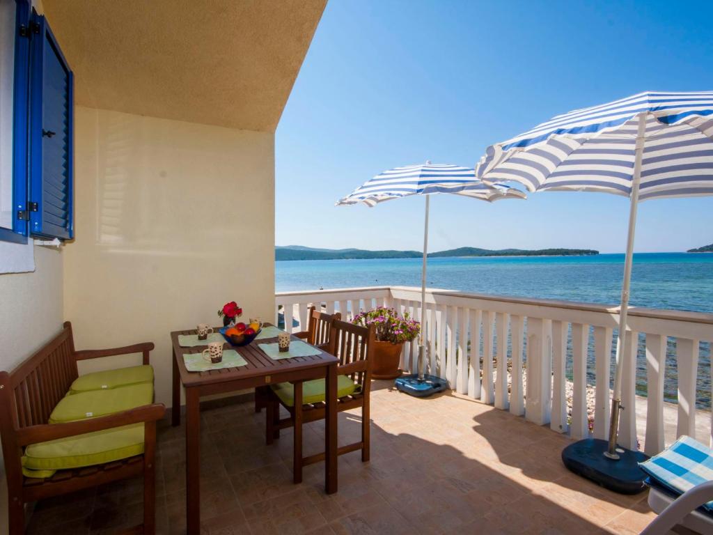 a balcony with a table and chairs and an umbrella at Apartments Grivičić in Krapanj