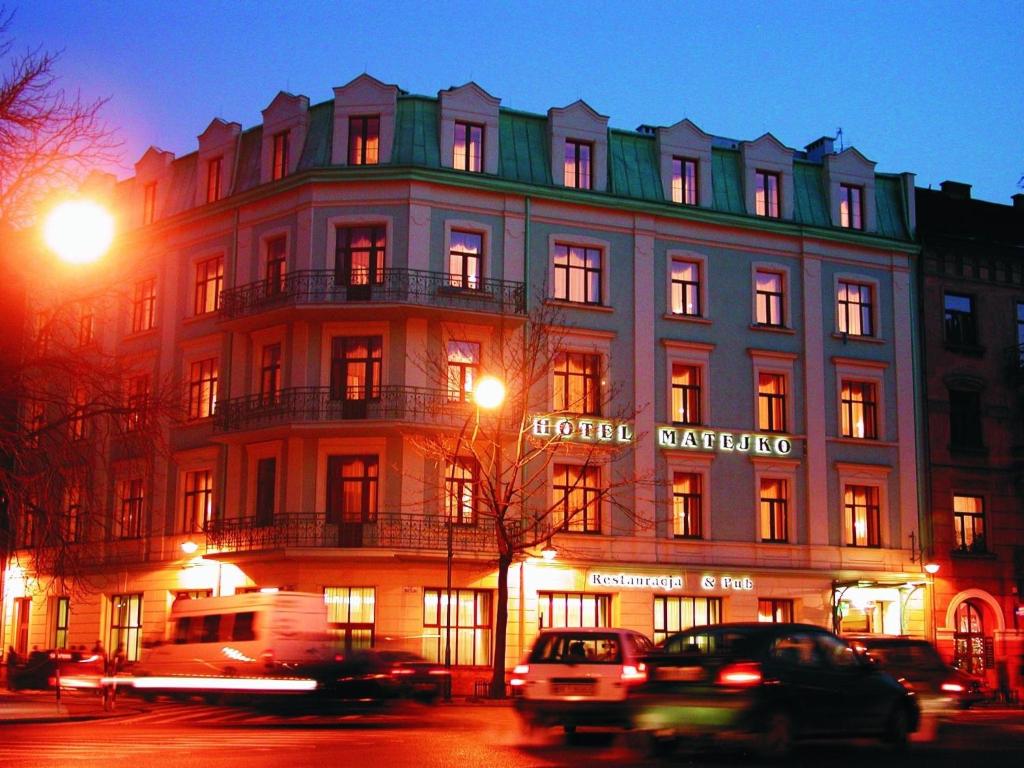 duży budynek z samochodami zaparkowanymi przed nim w obiekcie Matejko Hotel w Krakowie