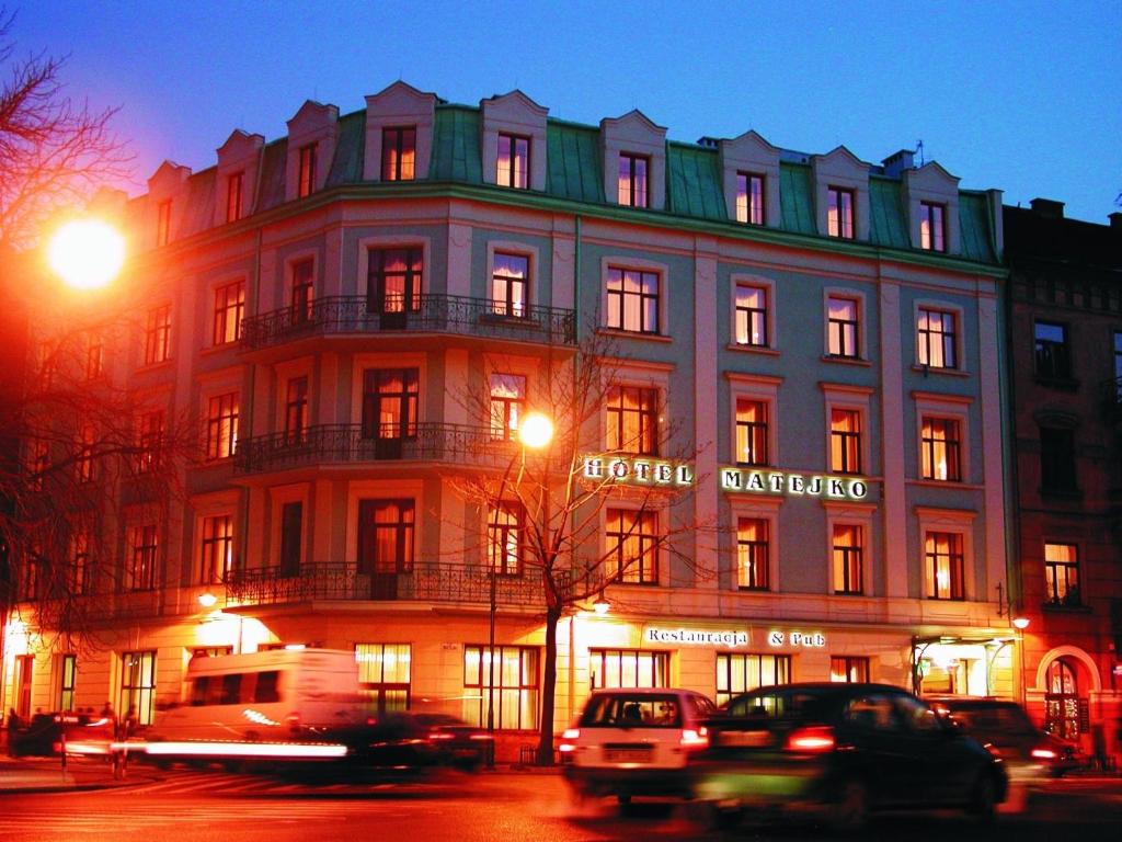 un gran edificio con coches estacionados frente a él en Matejko Hotel, en Cracovia