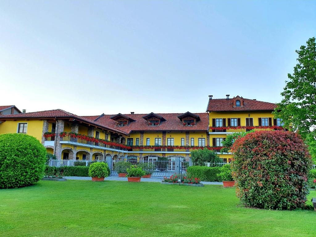 un gran edificio amarillo con un patio verde en Agriturismo La Desiderata, en Agliè