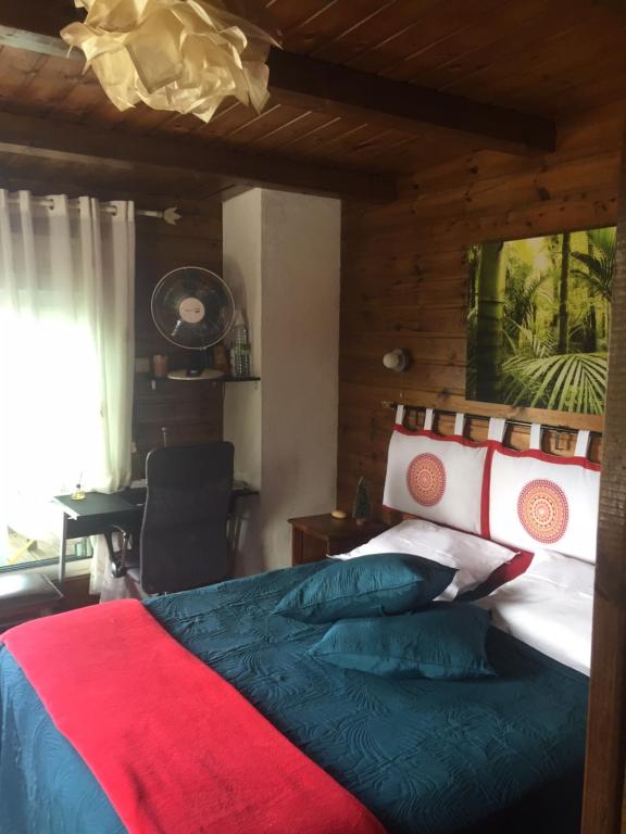Schlafzimmer mit einem Bett mit einer roten und blauen Decke in der Unterkunft COEUR CREOLE in Le Tampon