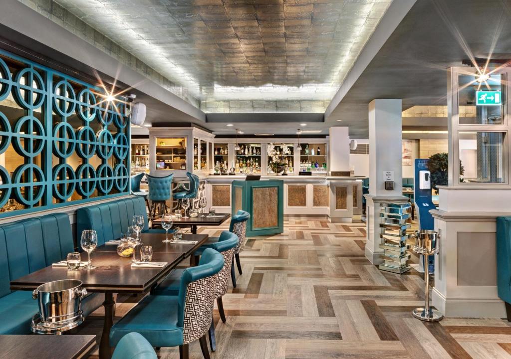 a restaurant with wooden tables and blue chairs at The West Park Hotel in Harrogate