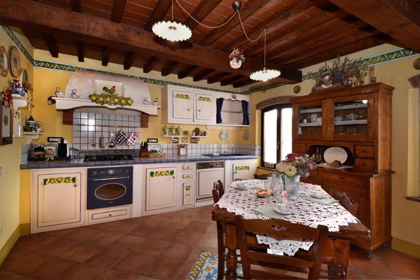 una cucina con tavolo e una cucina con pareti gialle di Casetta Rossa a Certaldo