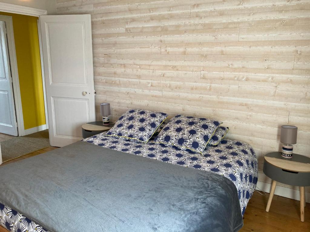 a bedroom with a bed and two tables and a wall at L'escale Granvillaise in Granville
