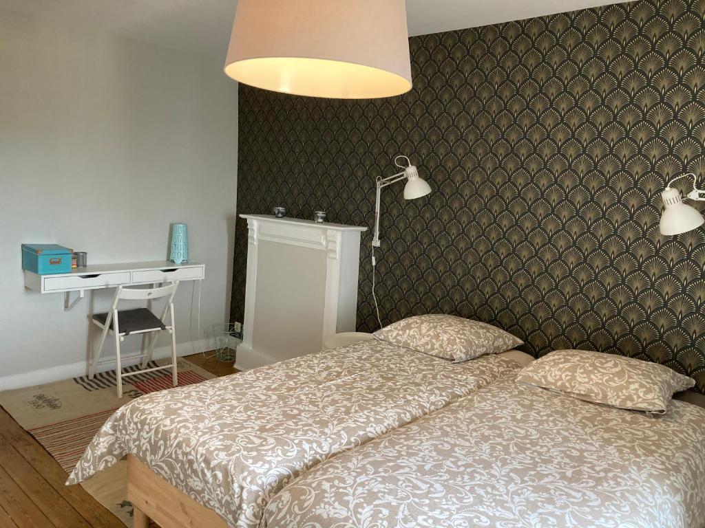 a bedroom with a bed and a desk and a lamp at L'escale Granvillaise in Granville