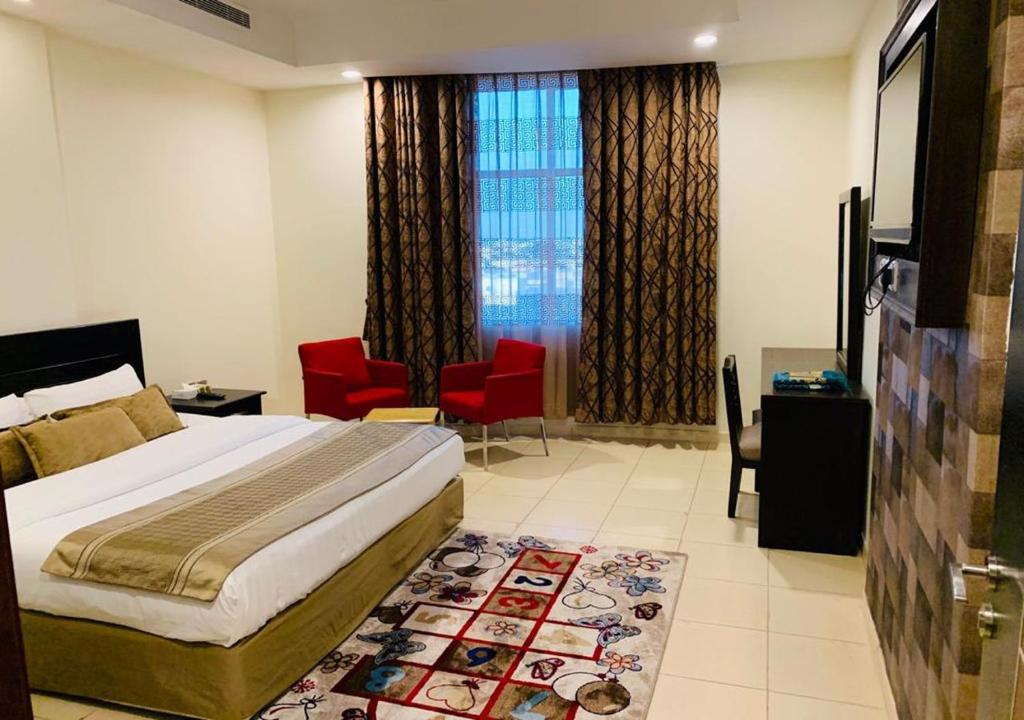 Mira Suites Prince Sultan Street-Jeddah في جدة: غرفة بالفندق سرير وكراسي حمراء