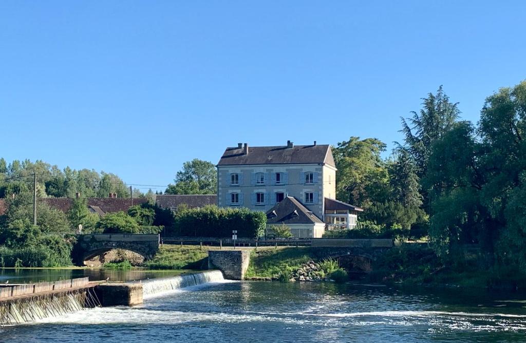 un gran edificio blanco sentado junto a un río en Le Moulin Du Port, en Saint-Georges-sur-Cher