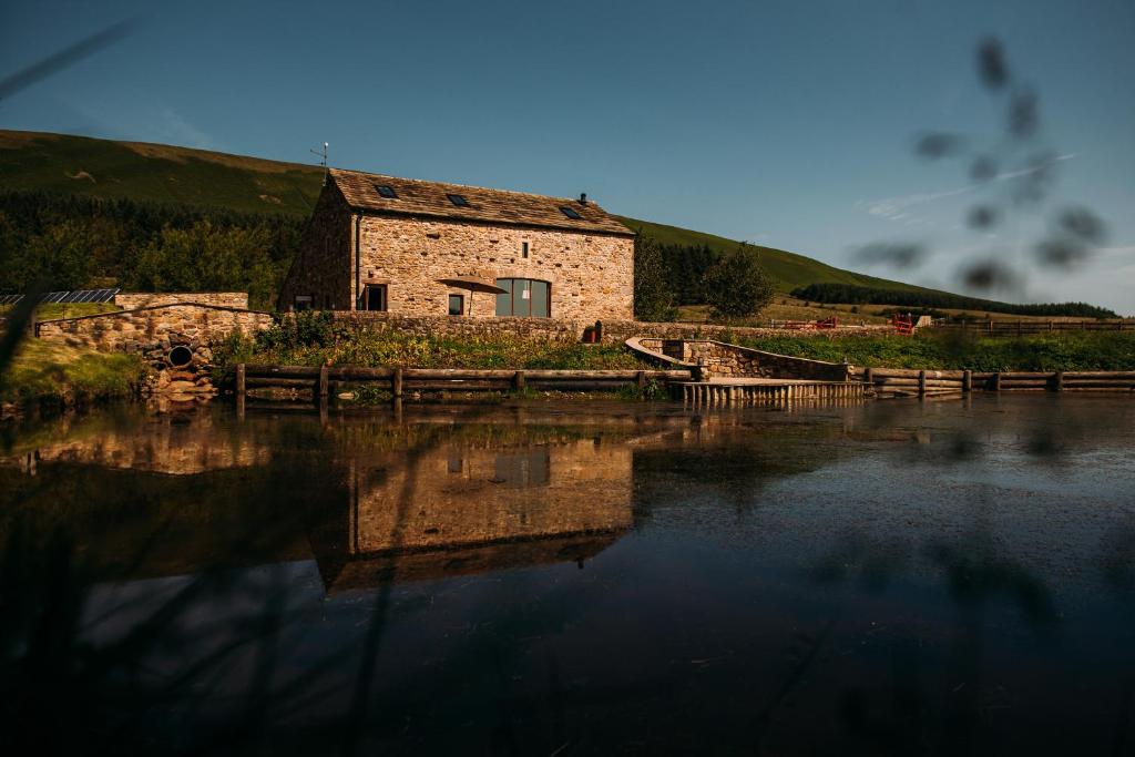 an old stone building sitting next to a body of water at Laythams Holiday Lets Retreat in Slaidburn
