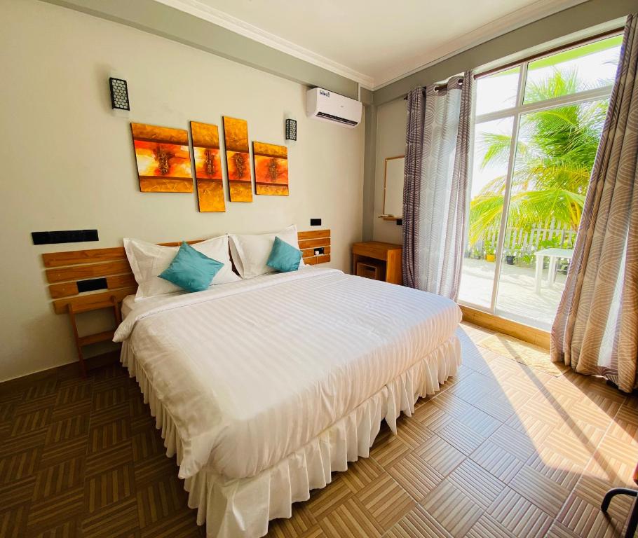 a bedroom with a bed and a large window at IRIS Beach Residence in Guraidhoo