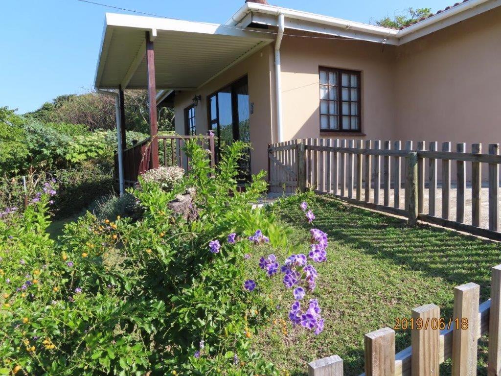 a house with a fence and flowers in the yard at Coral Cottage in Port Shepstone