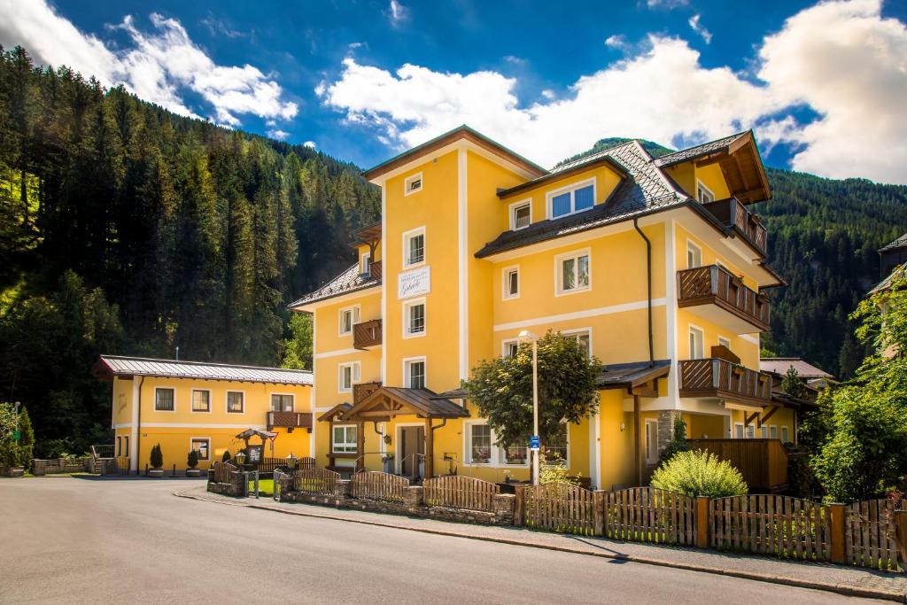 una casa gialla sul lato di una strada di Pension Appartements Gabriele a Bad Gastein