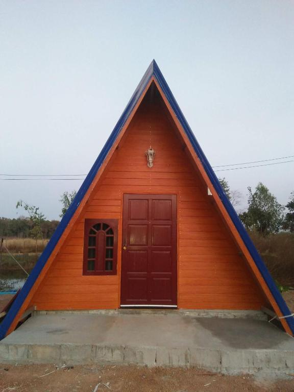 a small house with a pointed roof at บ้านพักกลางนา in Amphoe Sawang Daen Din