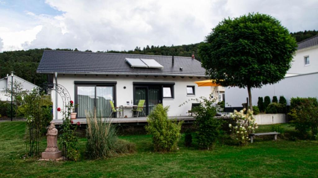 a white house with a porch and a tree at Die Pfalzherberge in Waldfischbach-Burgalben