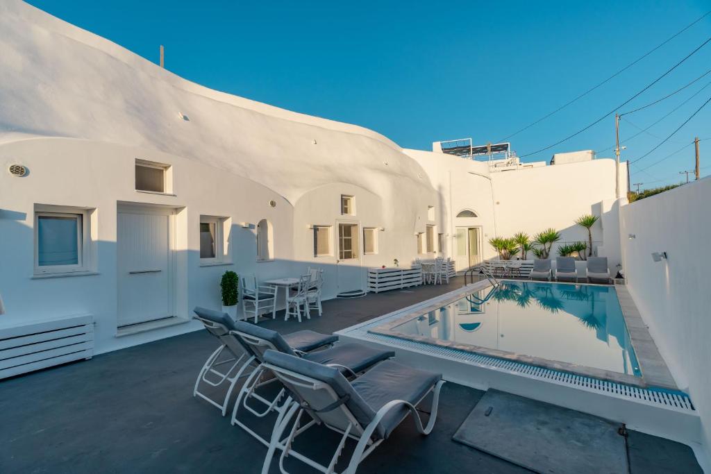 un patio avec des chaises et une piscine sur une maison dans l'établissement Fira-Cave-Sleeps 13-Parking-Pool-Pet Friendly, à Fira
