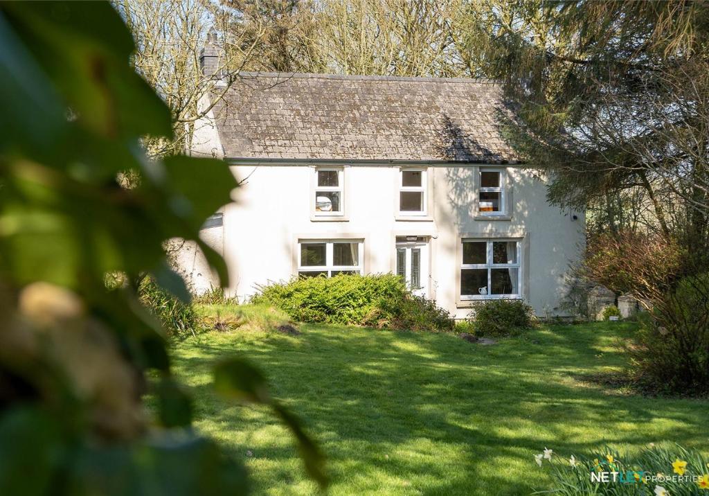 a white house with a roof on a lawn at Stone Hall Mill Cottage, Welsh Hook in Saint Lawrence