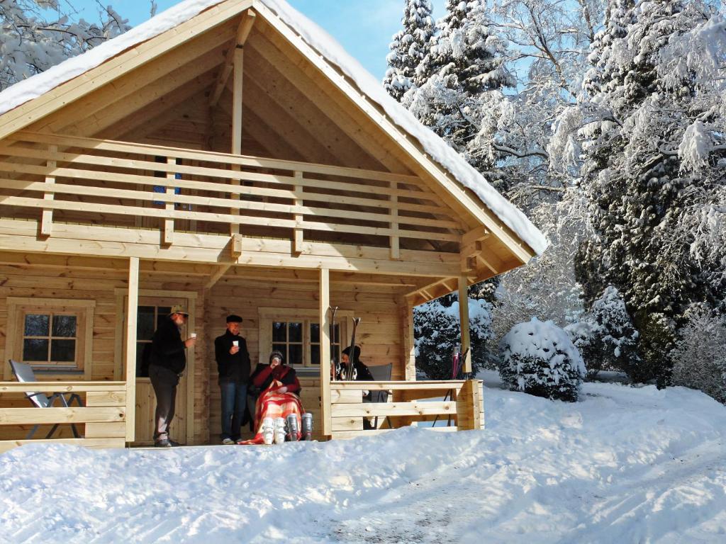 un groupe de personnes debout à l'extérieur d'une cabine dans la neige dans l'établissement Ferienpark Arber, à Zwiesel