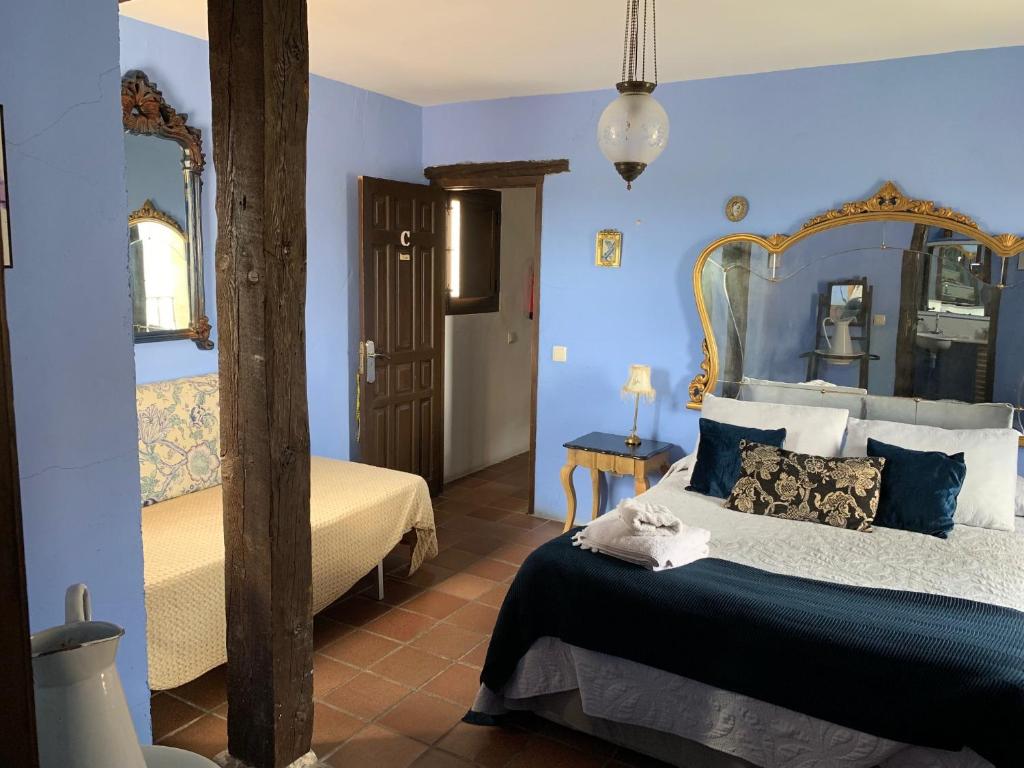 a bedroom with a bed with blue walls and a mirror at El Pósito in Hita