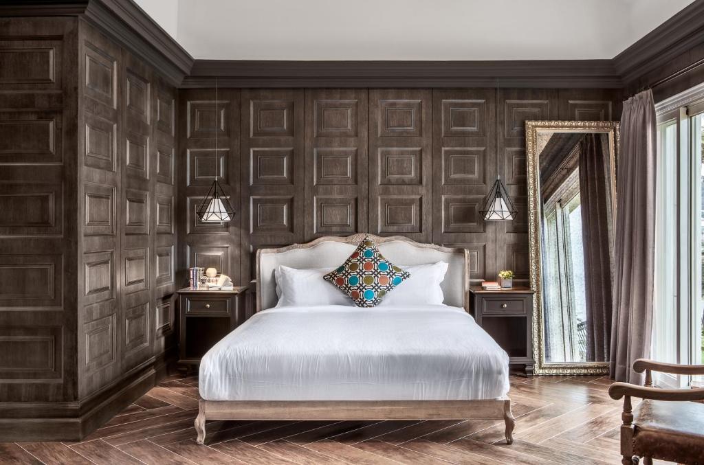 a bedroom with dark wood paneled walls and a white bed at Kenting 4 Sisters Villa in Eluan