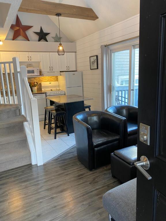 a living room with black leather chairs and a kitchen at Blue Mountain 2 Story Studio Loft in Blue Mountains