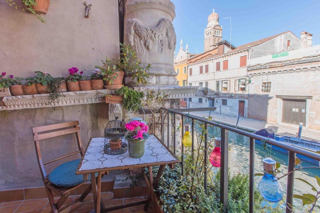 einen Tisch und einen Stuhl auf einem Balkon mit Blumen in der Unterkunft CA CAMMELLO private terrace and canal view in Venedig