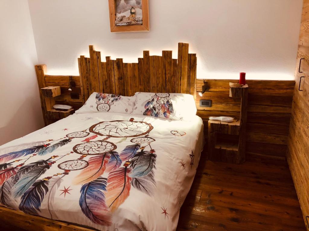 - une chambre avec un lit et une tête de lit en bois dans l'établissement Cèsa Mia, à Campitello di Fassa