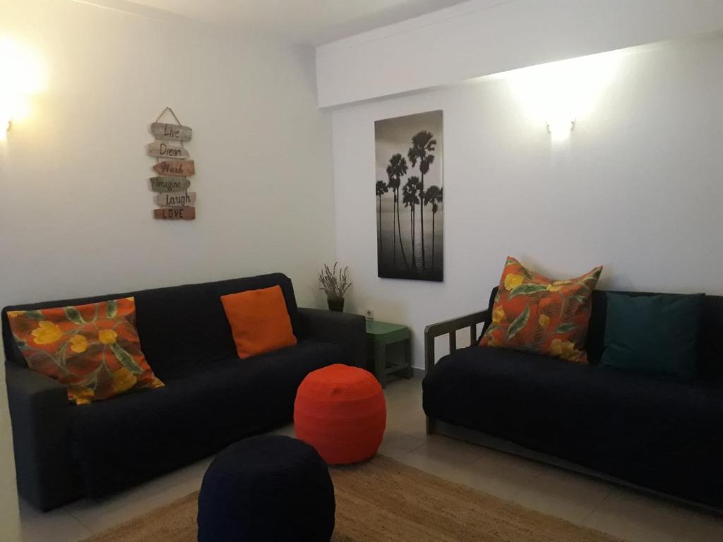 - un salon avec deux canapés noirs et un orb orange dans l'établissement Clube praia da rocha III, à Portimão
