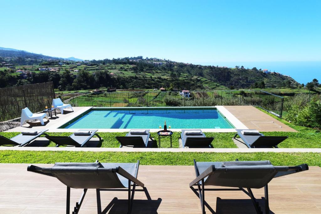 een zwembad met stoelen en uitzicht op een heuvel bij Beautiful Calheta Villa Villa Bella Vita 3 Bedrooms Stunning Sea Views Rural Setting in Calheta