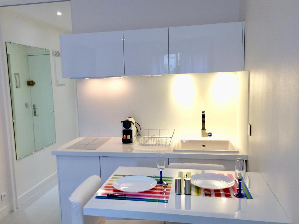 a white kitchen with a table with two plates on it at Paris Canal Studio - Gare de l'Est in Paris