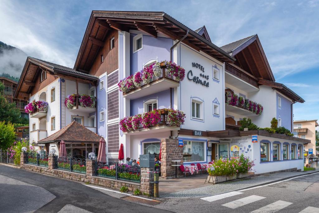 um grande edifício branco com caixas de flores em Hotel Cosmea em Ortisei