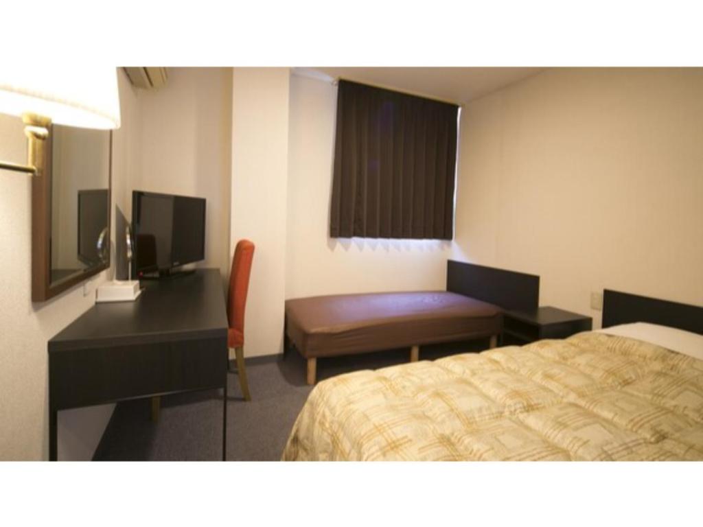 um quarto de hotel com um quarto com uma cama e uma secretária em Self inn Tokushima kuramoto ekimae - Vacation STAY 19489v em Tokushima