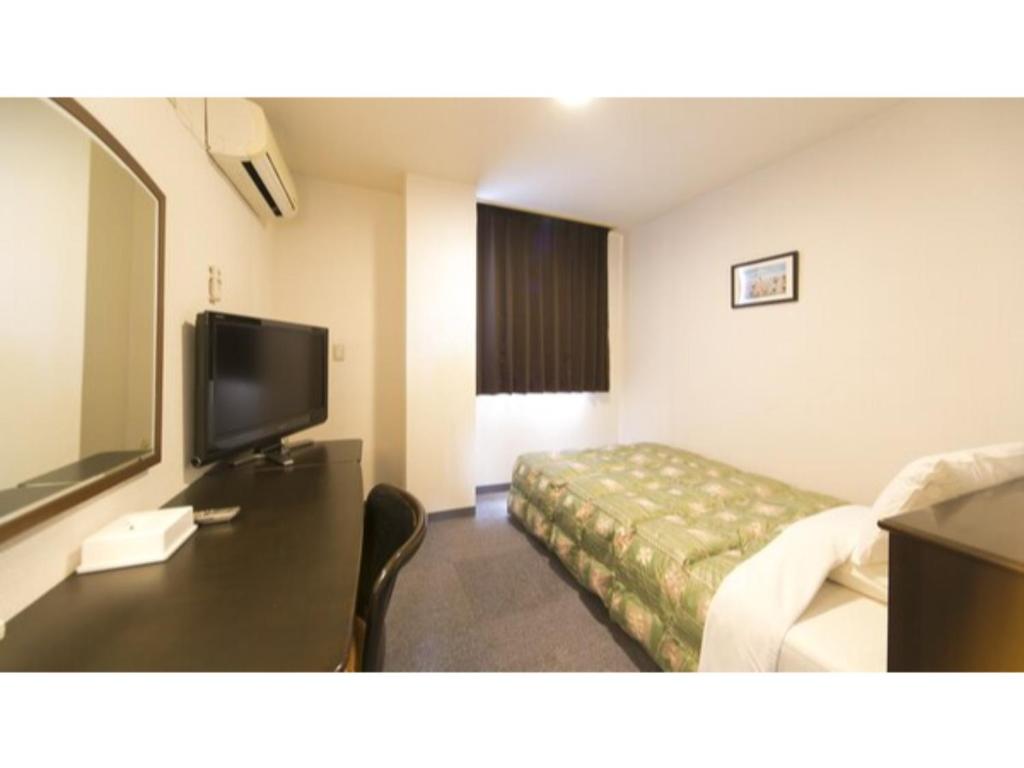 een hotelkamer met een bed en een flatscreen-tv bij Self inn Tokushima kuramoto ekimae - Vacation STAY 19478v in Tokushima