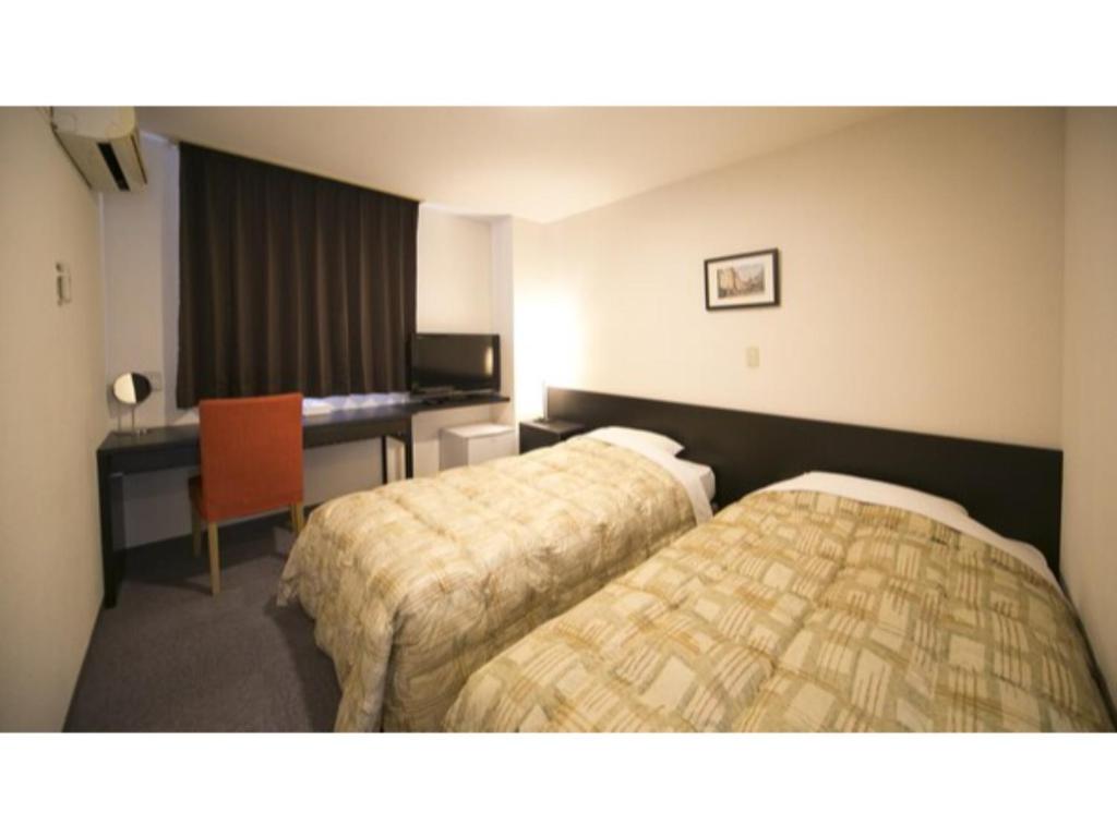 徳島市にあるSelf inn Tokushima kuramoto ekimae - Vacation STAY 19502vのベッド2台とデスクが備わるホテルルームです。