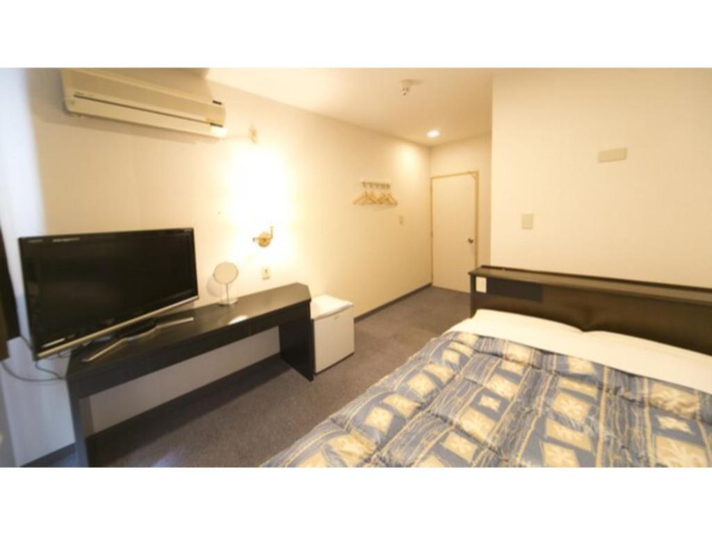 a hotel room with a bed and a flat screen tv at Self inn Tokushima kuramoto ekimae - Vacation STAY 19488v in Tokushima